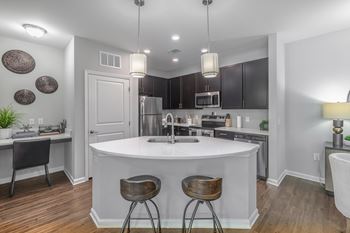 A kitchen with a white island and dark wood floors.
